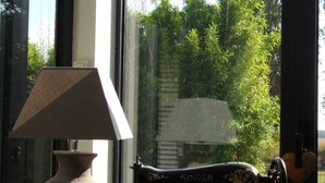 A sewing machine, a vase, and a lamp on a table by a window. - Chambres d'hotes Maison Prairie Bonheur (Magny-les-Hameaux)