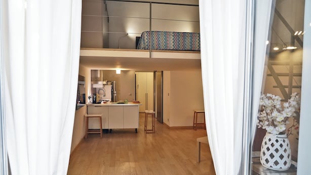 A modern interior with a kitchen area, a dining table, and a small seating area. - CATANIA HISTORICAL CENTER APARTMENT - LA PETITE SUITE ON 2 LEVELS. (catania)