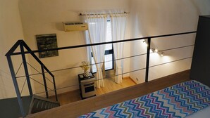 A staircase with a zigzag patterned rug, a small table with a vase, and a window with white curtains. - CATANIA HISTORICAL CENTER APARTMENT - LA PETITE SUITE ON 2 LEVELS. (catania)