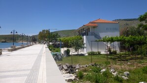 Un edifici costaner anomenat RIVIERA amb teulada de rajola, un passeig pavimentat i vista al mar.