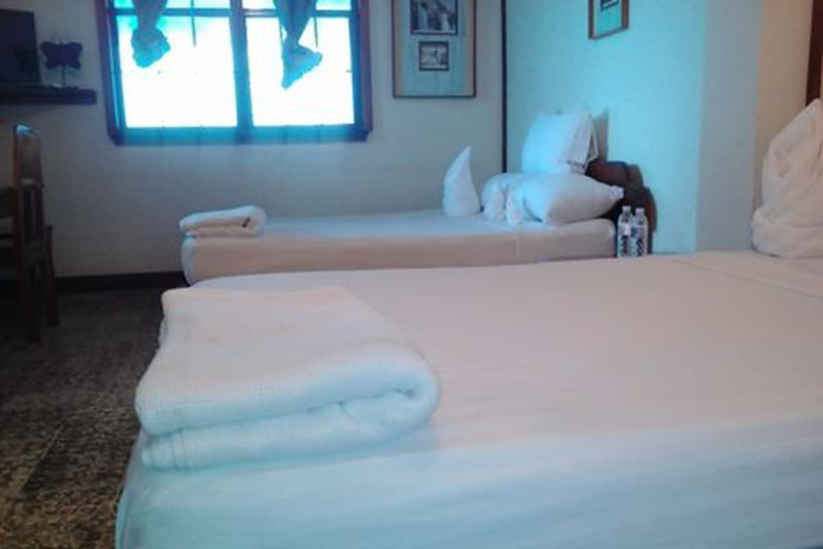 Una habitación de hotel con dos camas, una ventana con cortinas, una mesita y una silla.