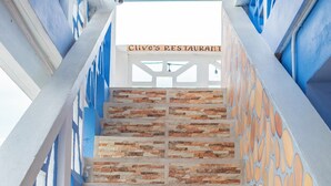 Una escalera de piedra con barandales azules que conduce a un restaurante llamado "Clive's Restaurant".