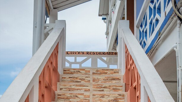 Una escalera de piedra con barandales blancos que conduce a un edificio con un letrero que dice 'Clive's Restaurant'.