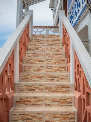 A staircase with stone steps leading to a building with a sign that reads 'Clive's Restaurant'. - Sea Front Inn (Punta Gorda)