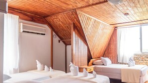 Habitación de hotel con dos camas, techo de madera y pared de piedra.