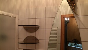Un baño con un lavabo blanco, un espejo, un perchero para toallas y un detalle decorativo de pan de oro en la pared.