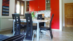 Un comedor con una mesa y sillas, un jarrón con flores y armarios rojos.