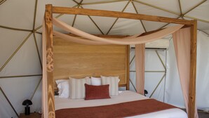 A bed with a wooden frame, white bedding, and a brown throw blanket.