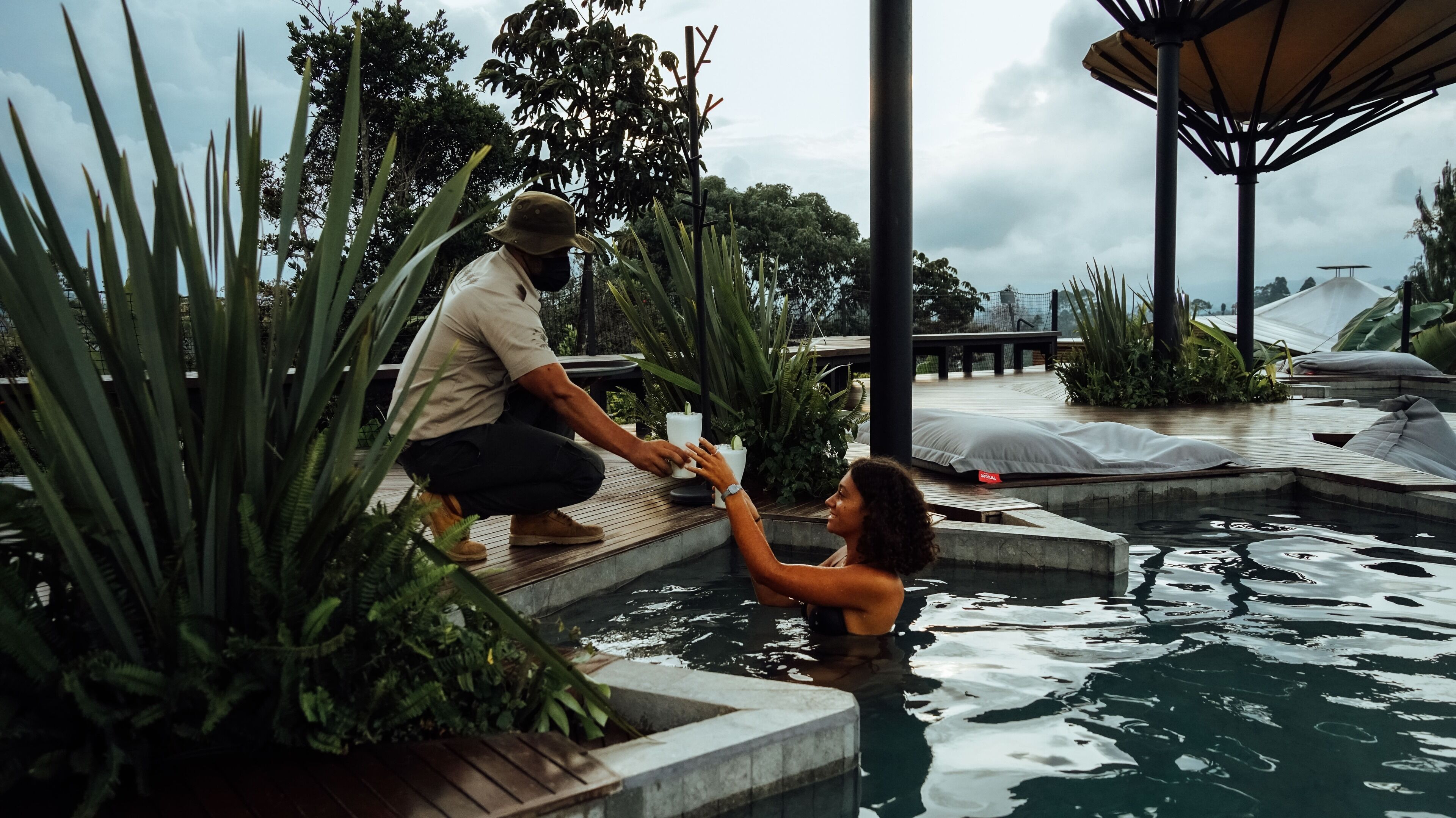 A pool area with steps leading into the water, surrounded by tropical plants.