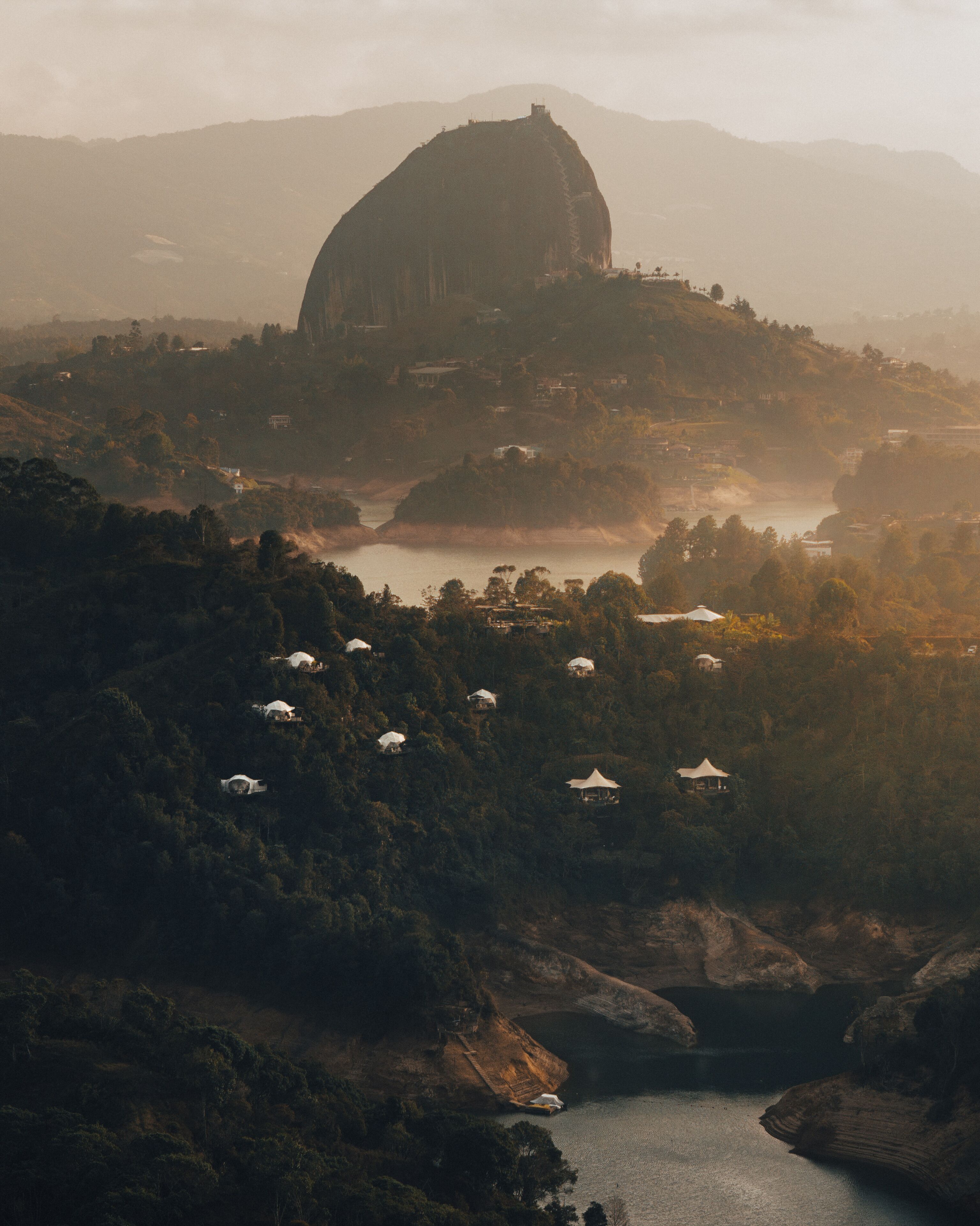 A large dome-shaped building surrounded by lush greenery and a body of water.