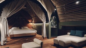 A cozy bedroom with a large bed, a sofa, and a reading area.