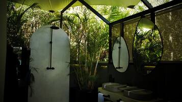 Une salle de bain dotée d’un grand miroir, de deux lavabos et d’un espace douche.
