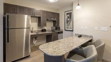 A modern kitchen with stainless steel appliances, granite countertops, and a bar seating area.