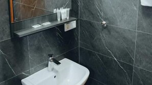 A modern bathroom with a white sink, dark marble walls, and a mirror with a towel rack. - Angelis Pension Frankfurt Airport (Kelsterbach)