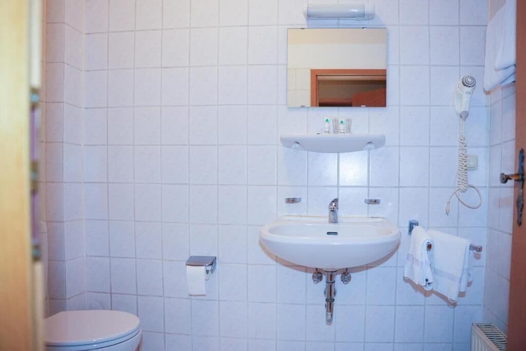 Ein Badezimmer mit Toilette, Waschbecken, Spiegel und Föhn.
