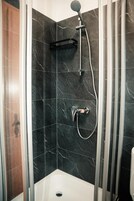 A shower with a handheld showerhead and a wall-mounted faucet.