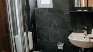 A bathroom with a glass shower enclosure, a toilet, a sink, and a mirror. - Angelis Pension Frankfurt Airport (Kelsterbach)