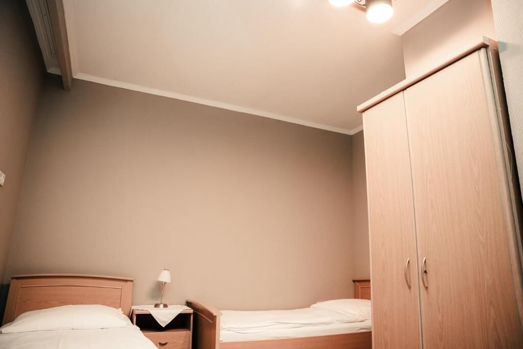 Un dormitorio con dos camas, una mesita de noche con lámpara y un armario.