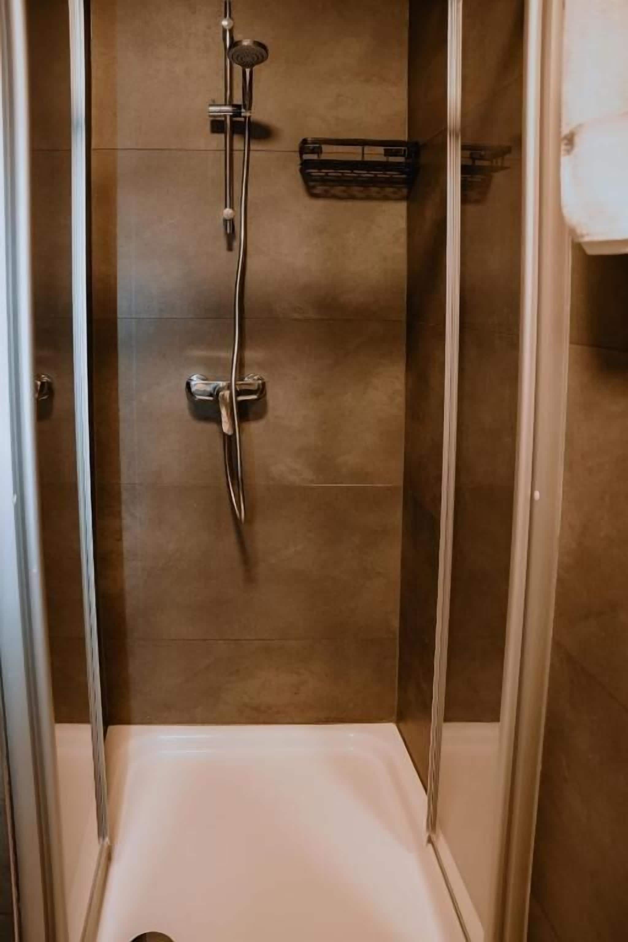 Eine begehbare Dusche mit Duschbrause, Handfaucet und Bedienfeld.