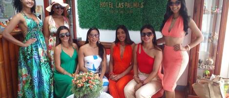 A group of people in a room with a green wall and a sign that reads "Hotel Las Palmas."