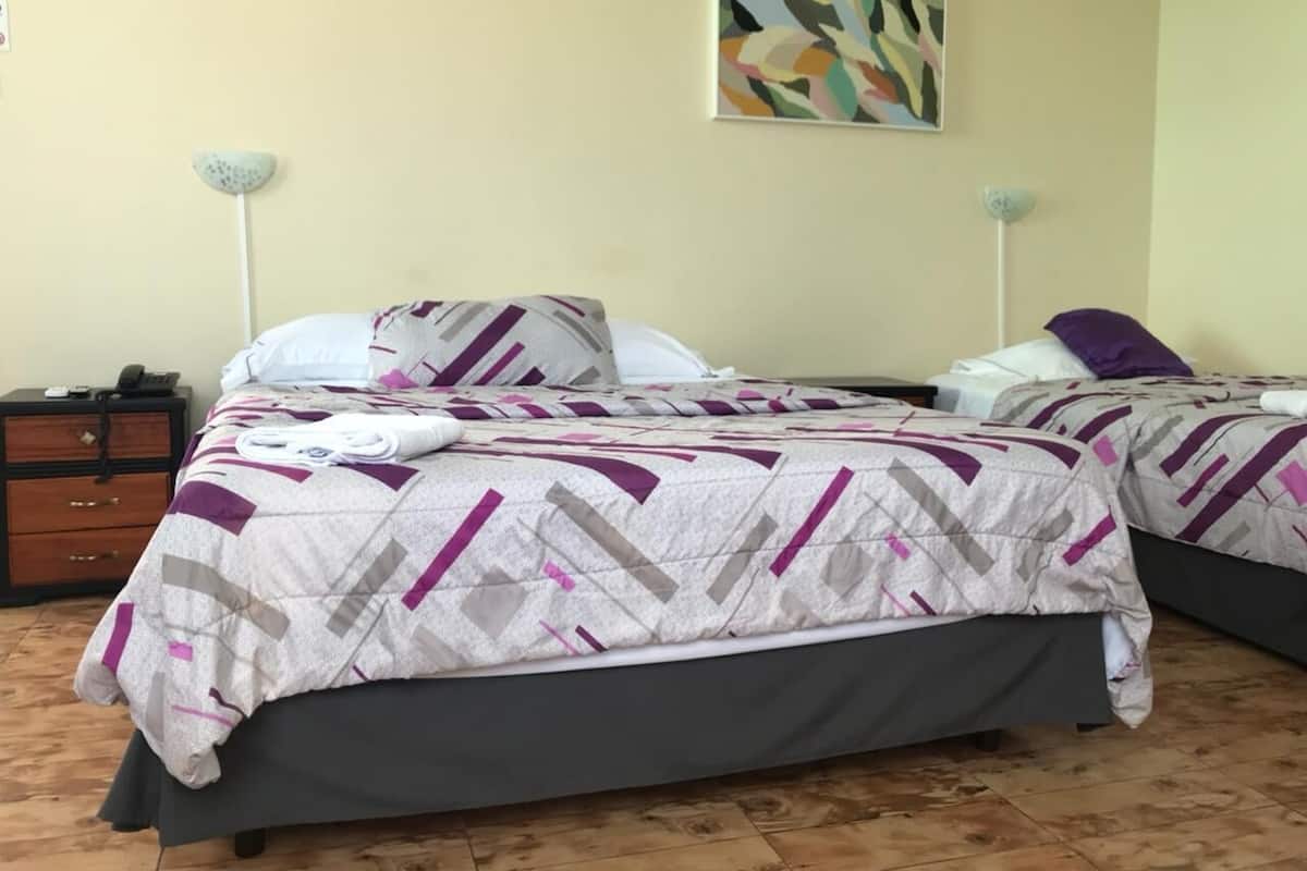 A room with two beds, a wooden dresser, and a painting on the wall.
