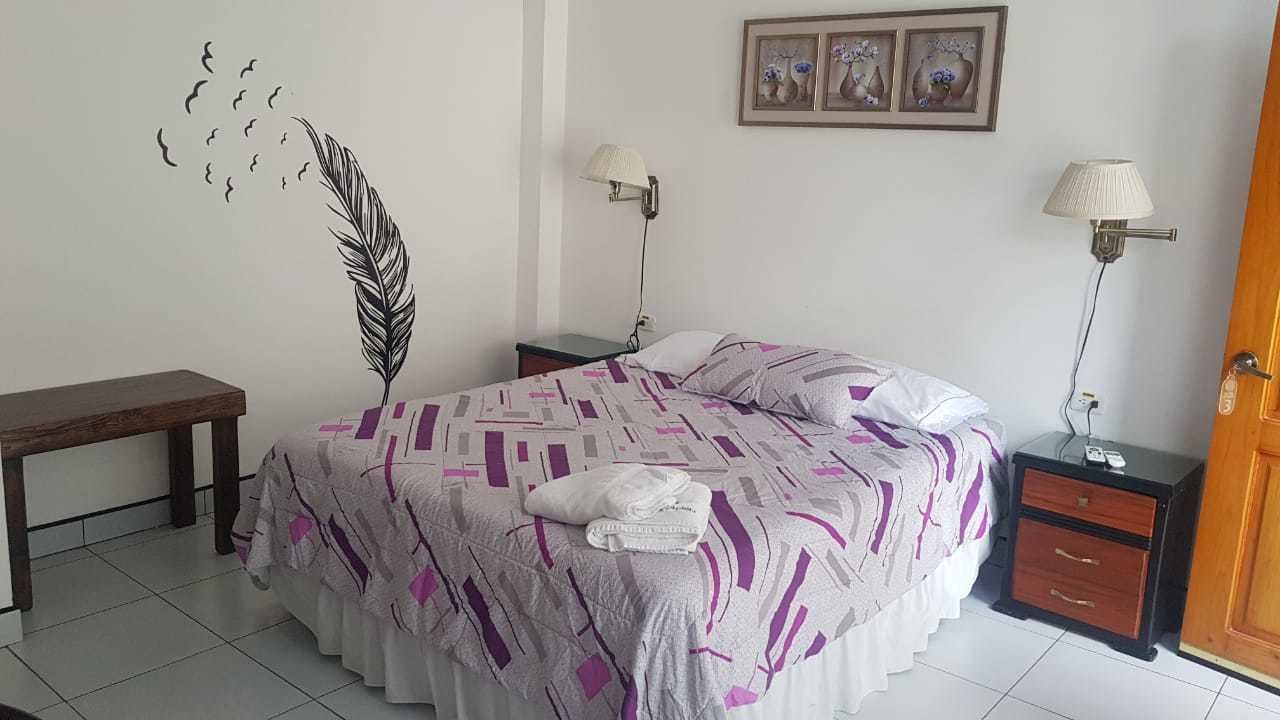 A bedroom with a bed, bedside tables, a bench, and wall decorations.