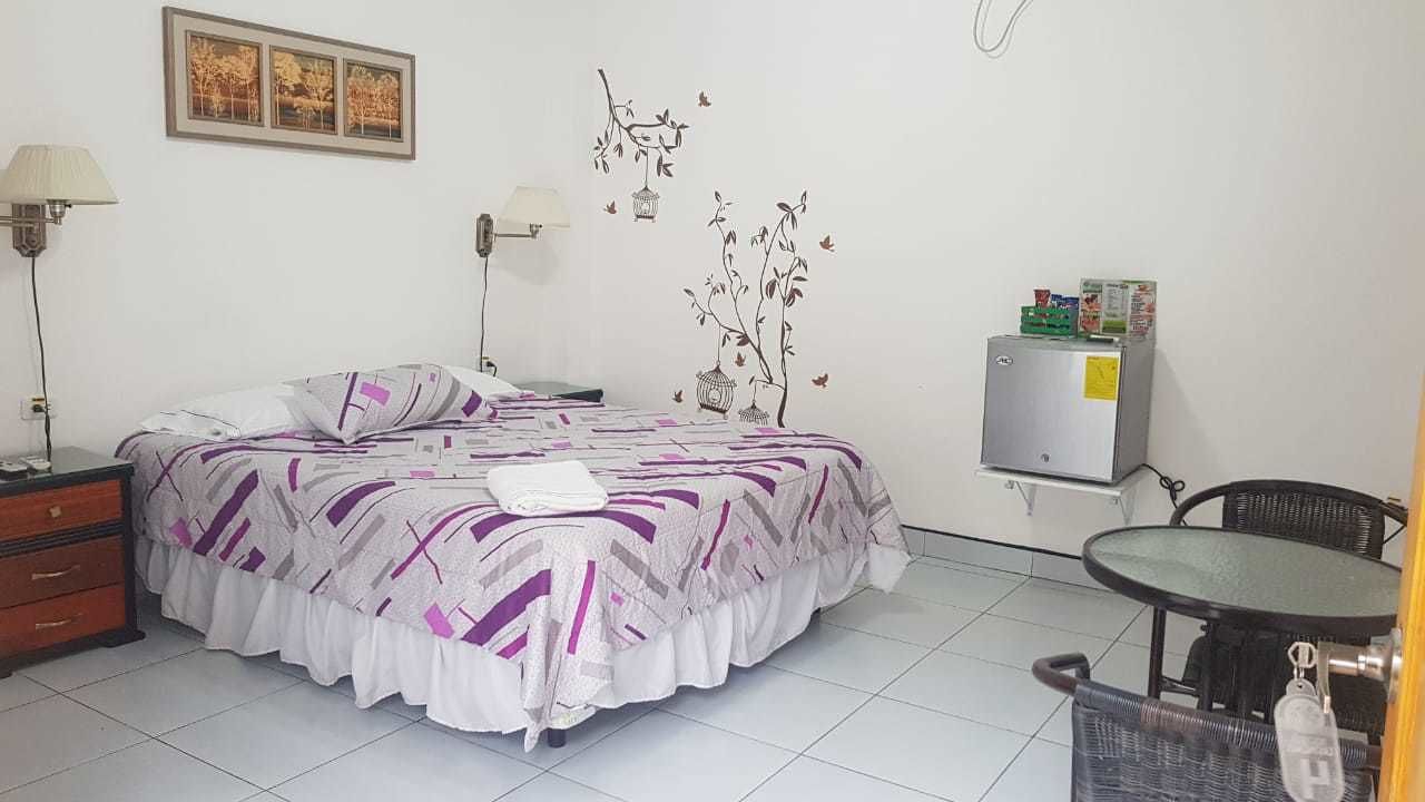 Une chambre d’hôtel équipée d’un lit, d’un bureau, d’une chaise, d’une lampe et d’un réfrigérateur.