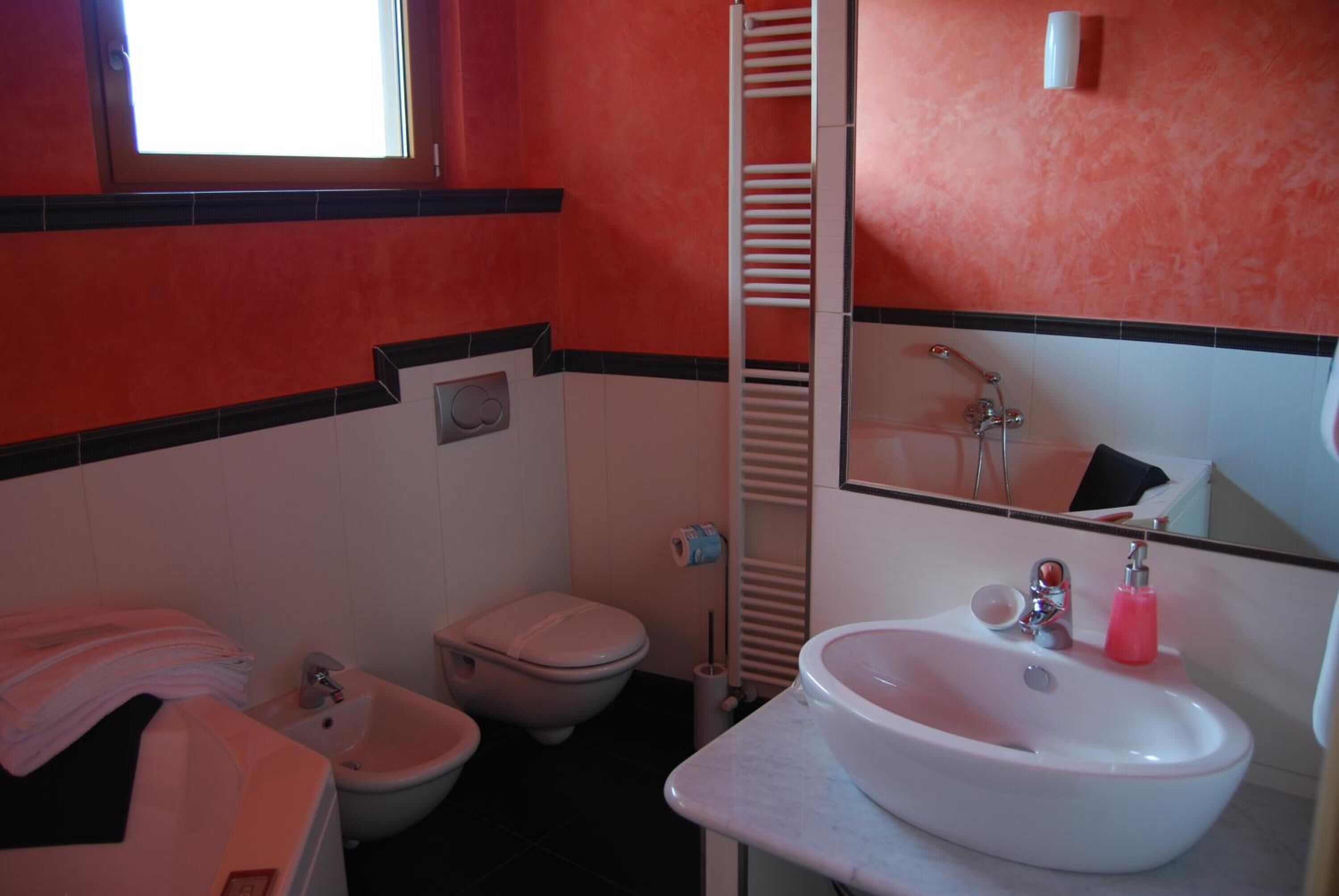 A bathroom with a toilet, bidet, sink, and a towel rack.