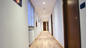 A hallway with wooden flooring, white walls, and a door on the right.