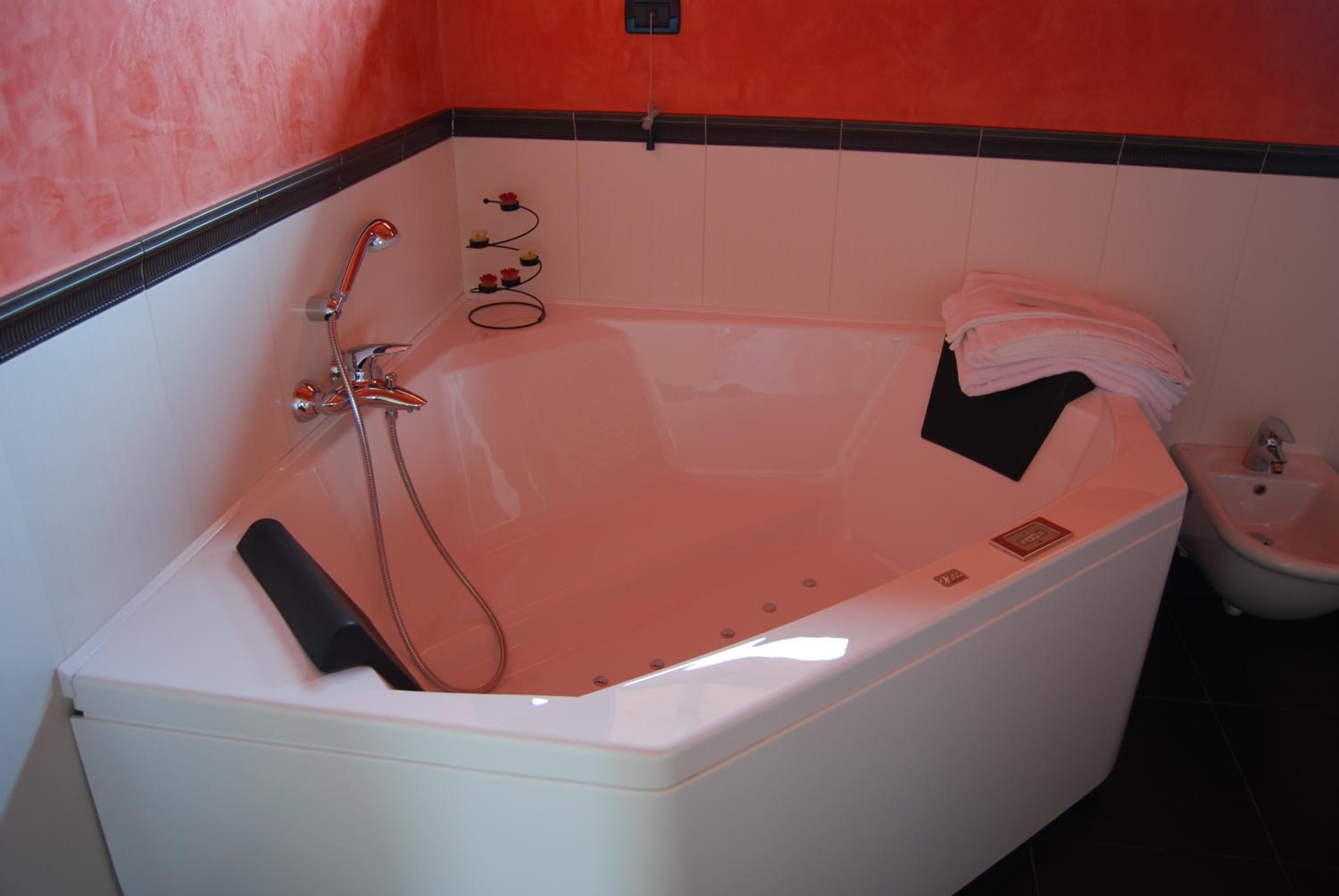 Ein modernes Badezimmer mit einer großen Badewanne, einer Duschbrause und einem kleinen Waschbecken.