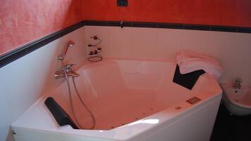 Ein modernes Badezimmer mit einer großen Badewanne, einer Duschbrause und einem kleinen Waschbecken.