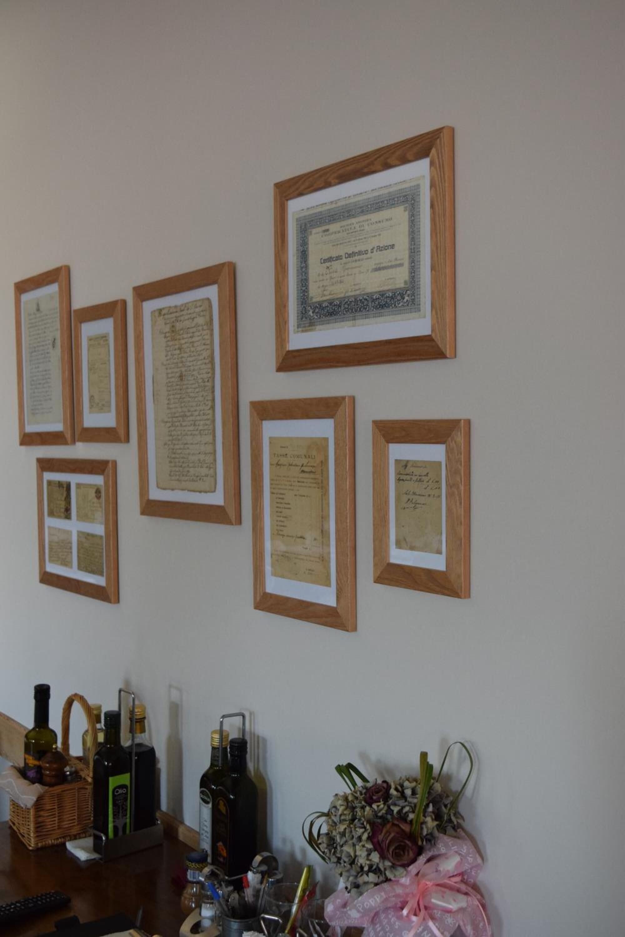 Una habitación con documentos enmarcados en la pared, una mesa con botellas y un ramo de flores.