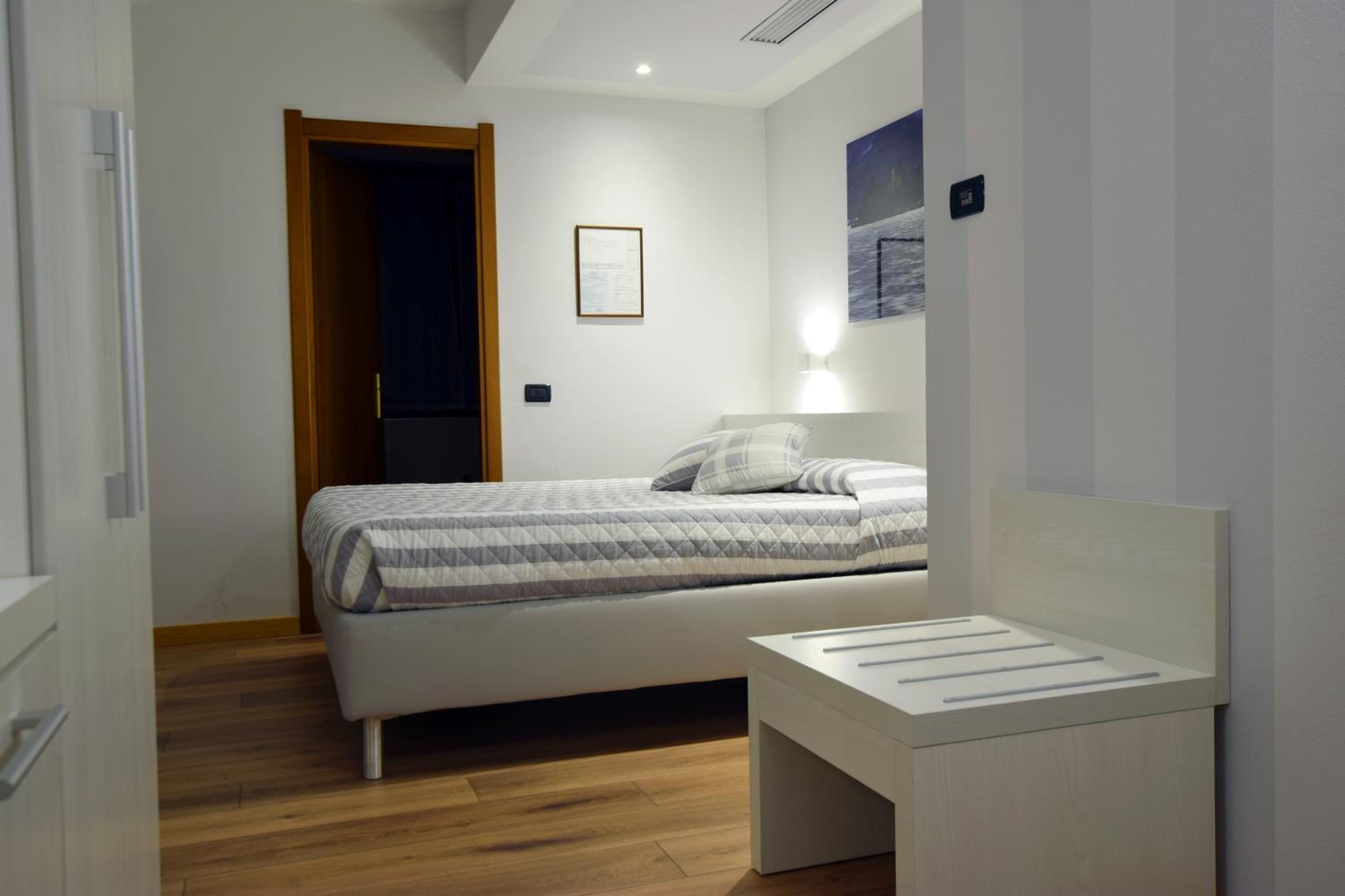 Un dormitorio moderno con cama, mesita de noche y un cuadro enmarcado en la pared.