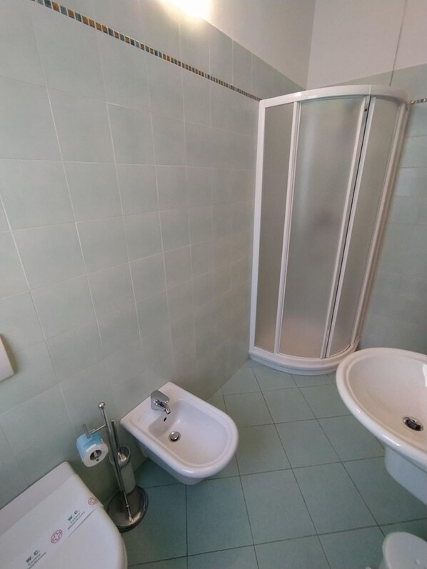 A bathroom with a shower, bidet, and two sinks.