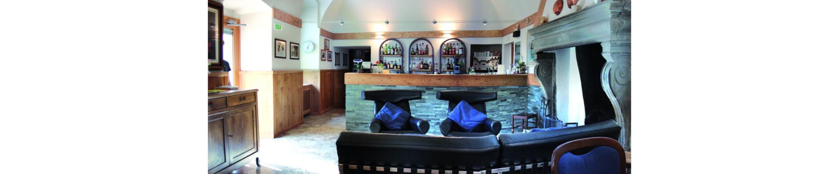 Eine Bar mit Steinwand, Holztresen und Barhocker.