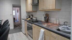 Une cuisine moderne avec des meubles en bois, un plan de travail noir et une hotte en acier inoxydable.