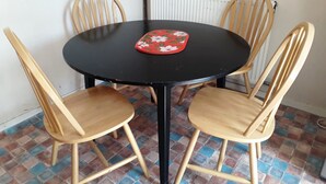 Une table ronde avec un plateau noir et quatre chaises en bois dotées d’assises rembourrées.