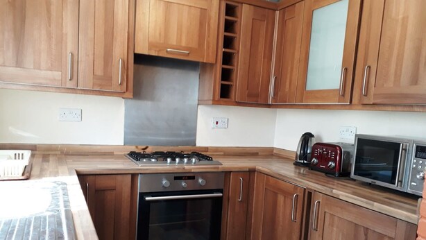 Une cuisine avec des meubles de rangement en bois, une cuisinière à gaz, un four, un four à micro-ondes et un grille-pain.