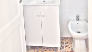 A bathroom with a white sink, mirror, and bidet. - Hostel Triúno (Lisbon)