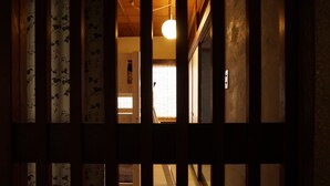 Un intérieur japonais traditionnel avec un sol recouvert de tatamis, des portes coulissantes et un luminaire suspendu.
