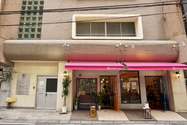 A building with a large window, a door, and a pink awning.