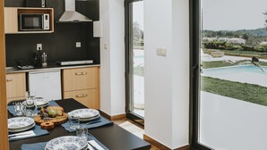 A modern kitchen with a dining area, a view of a swimming pool, and a large window. - Lugar nas Estrelas (Covilhã)