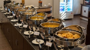 Un buffet proposant une variété de plats, chacun étant clairement identifié, notamment des plats comme le puri et le sabji d’alo gobi.