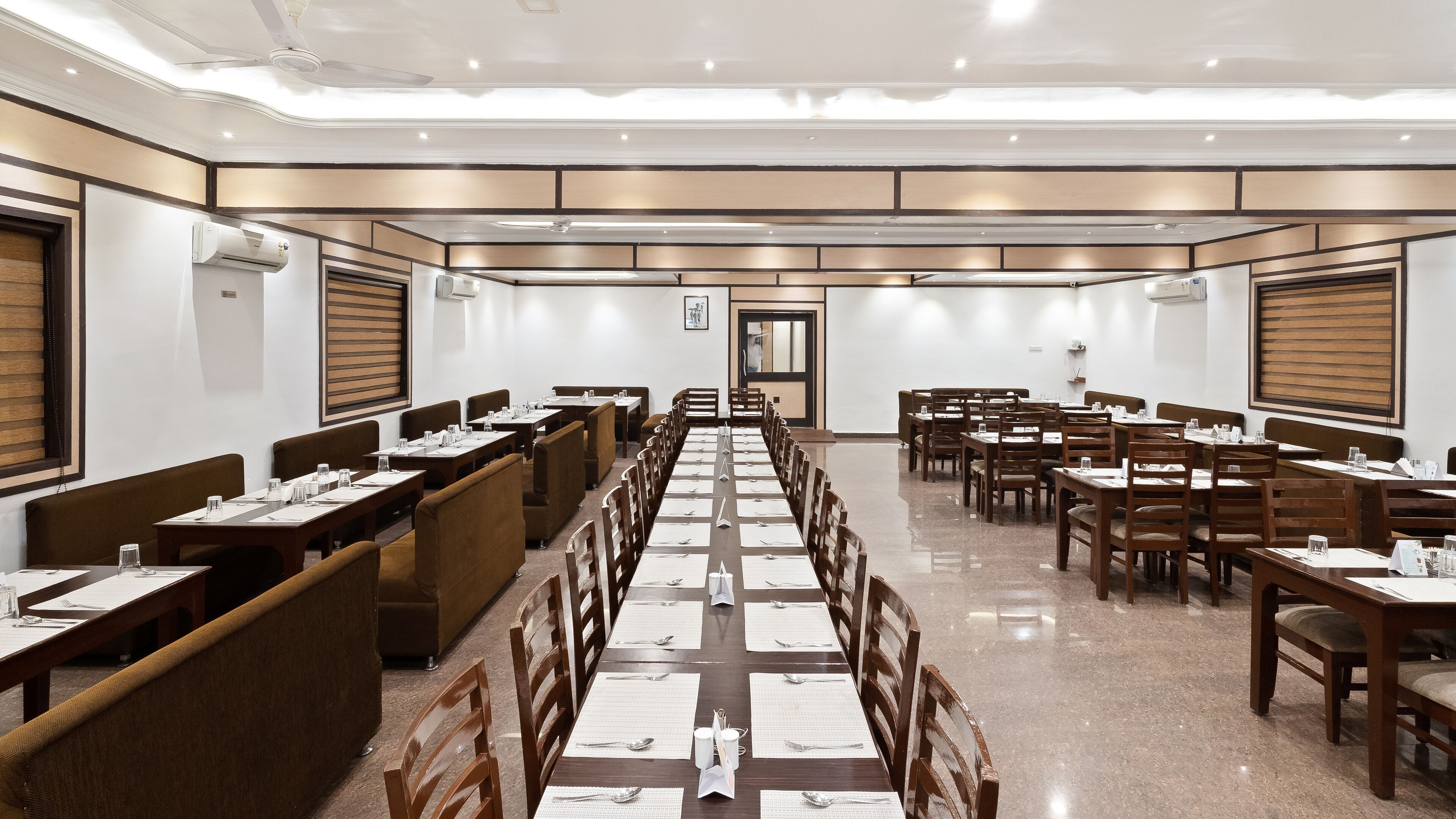 A conference room with long tables, chairs, and a polished floor.