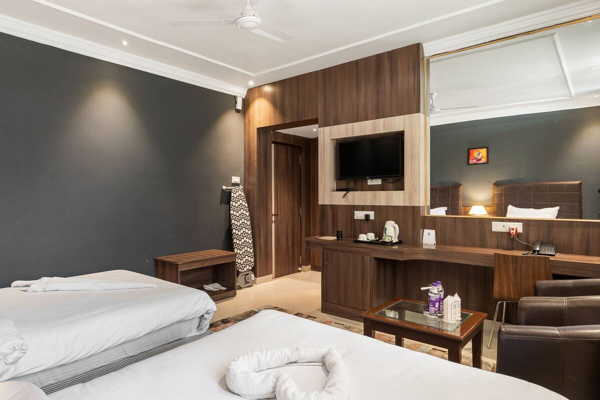 Een hotelkamer met een bed, een bureau met een computer, een televisie en een spiegel.