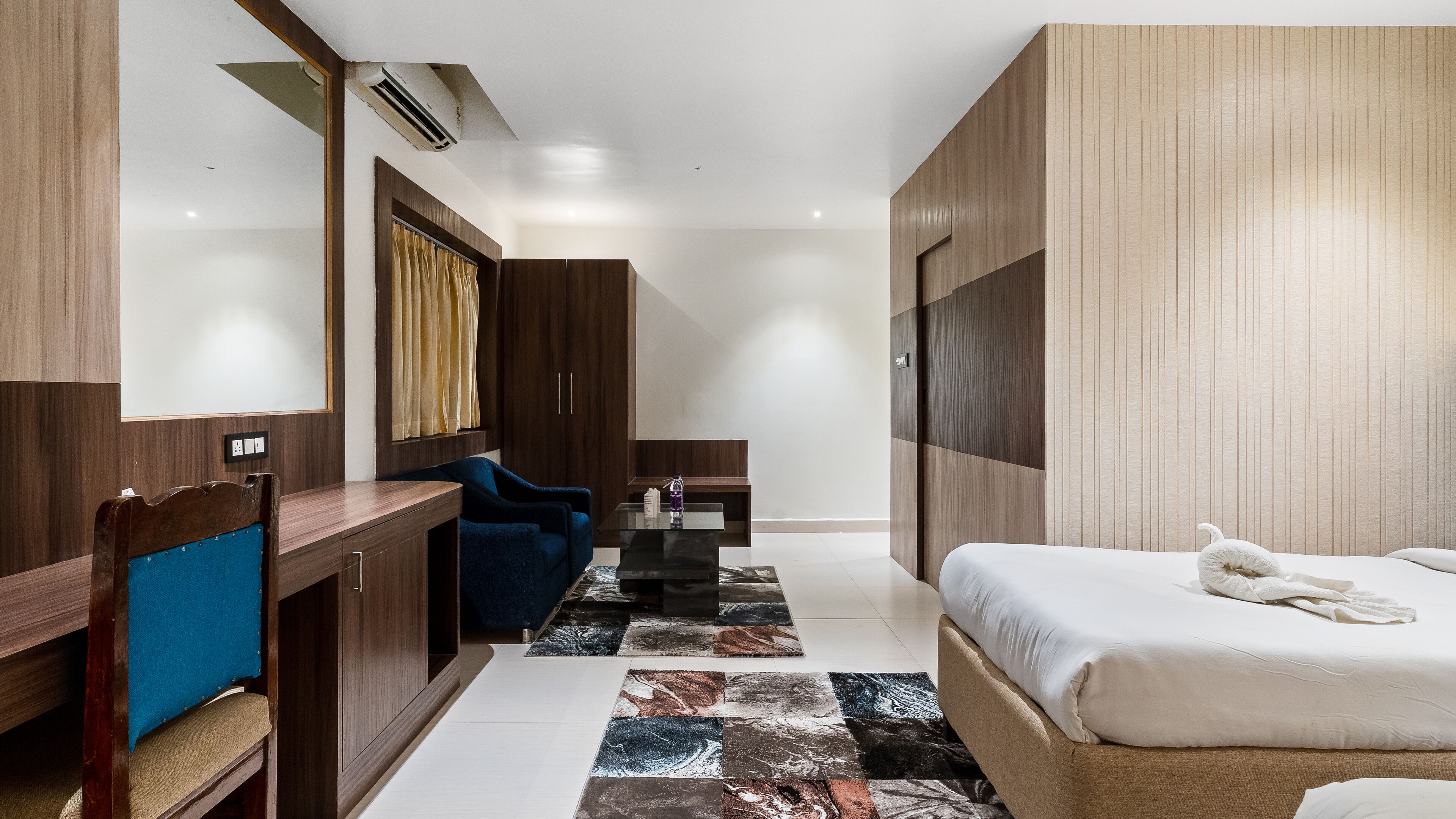 Een moderne hotelkamer met een bed, een bureau, een stoel en een klein tafeltje.