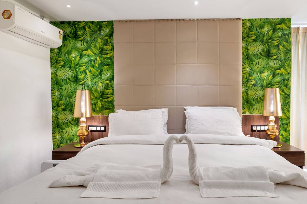 Een hotelkamer met een bed, twee bedlampen, een wandairconditioner en een raam met gordijnen.