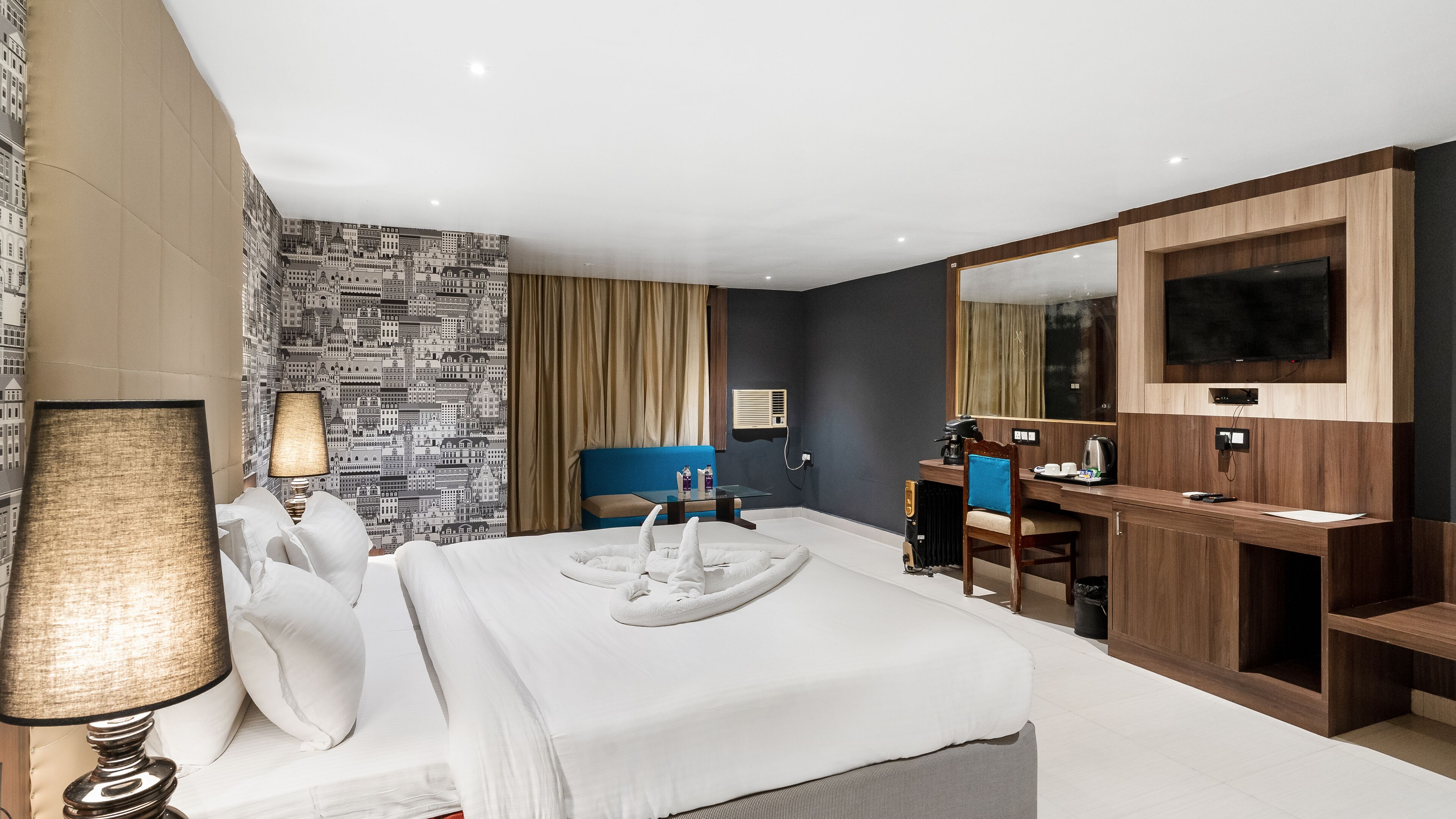 Ein Hotelzimmer mit einem großen Bett, einem Schreibtisch mit Stuhl, einem Fernseher und einem Badezimmerbereich.