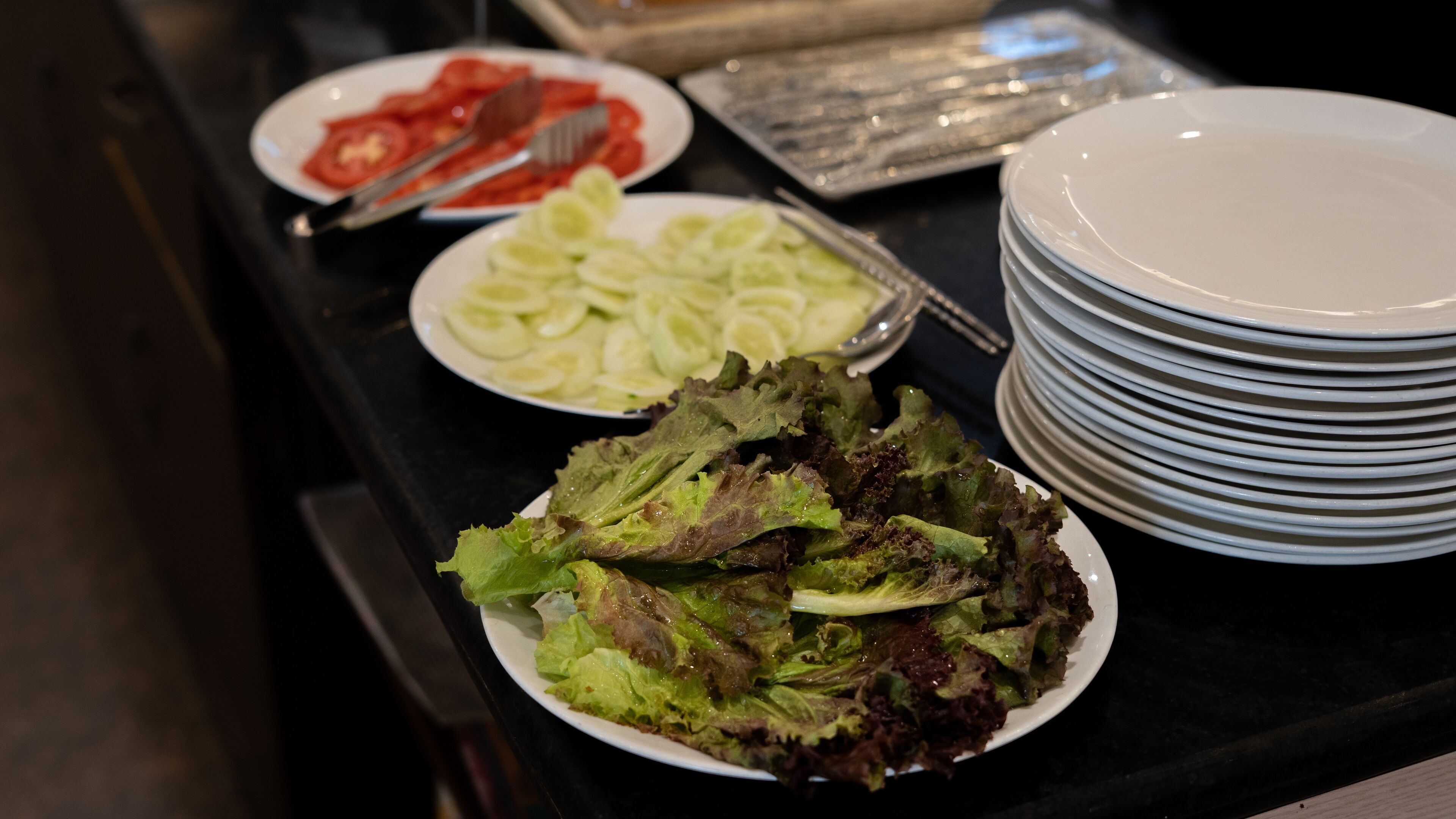 A buffet table with various salads and plates.