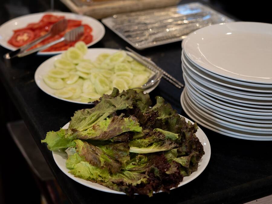A buffet table with various salads and plates.